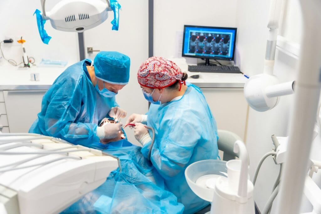 Clinica dentale, dentisti in tute blu che eseguono un impianto, vista dall’alto