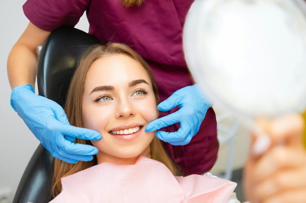 Dentista mostra il sorriso perfetto del paziente dopo l'applicazione di faccette dentali