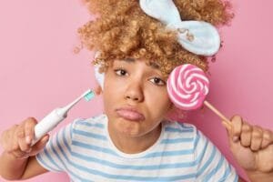 Dissatisfied woman has problems with teeth as eats many sweets suffers from caries holds electric to