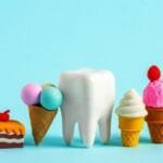 Human tooth model with tiny sweets. Unhealthy sweet food cases caries concept.