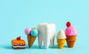 Human tooth model with tiny sweets. Unhealthy sweet food cases caries concept.