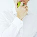 Photo of a businessman taking a bite of a green healthy apple