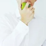 Photo of a businessman taking a bite of a green healthy apple