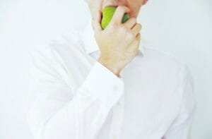 Photo of a businessman taking a bite of a green healthy apple