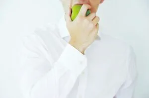 Photo of a businessman taking a bite of a green healthy apple