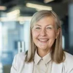 Close-up portrait of mature gray-haired business woman, senior adult woman smiling and looking at