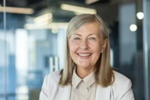 Close-up portrait of mature gray-haired business woman, senior adult woman smiling and looking at