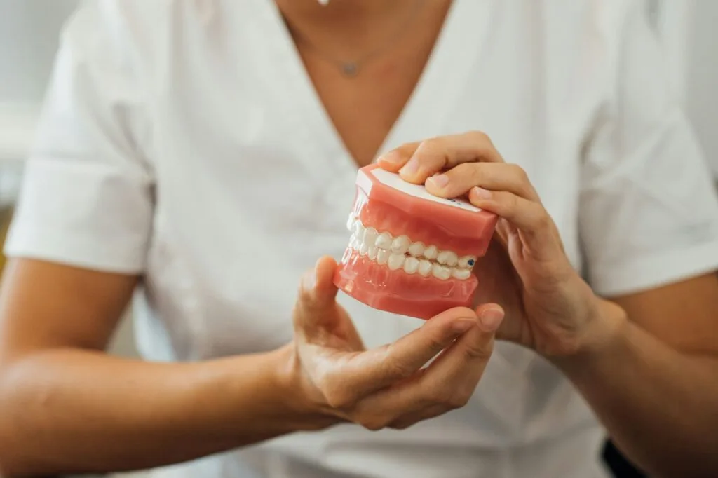 Vista parziale di un'infermiera che tiene in mano una dentiera mobile
